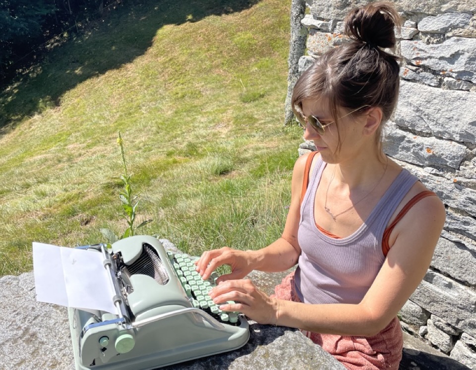 Elisa an Schreibmaschine auf der Alp während Yoga und Digital Detox.